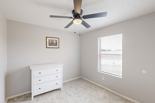 carpeted empty room featuring ceiling fan and a textured ceiling