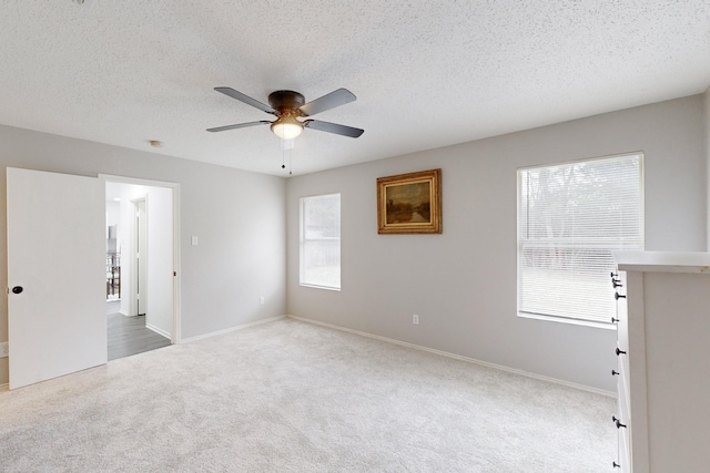 empty room featuring ceiling fan, light colored carpet, and a textured ceiling