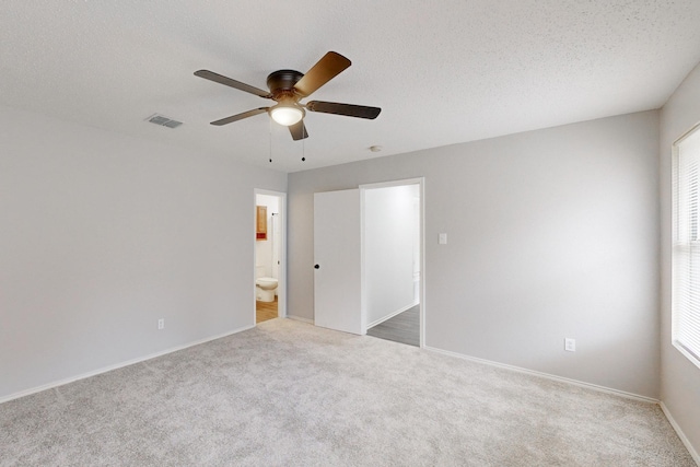 carpeted spare room with ceiling fan, a healthy amount of sunlight, and a textured ceiling