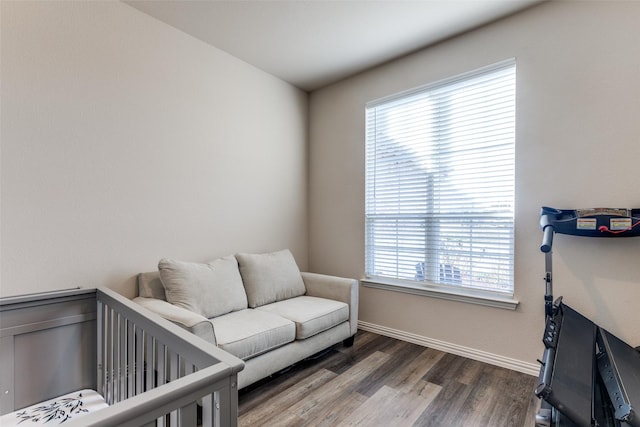 bedroom featuring a crib, dark hardwood / wood-style flooring, and multiple windows