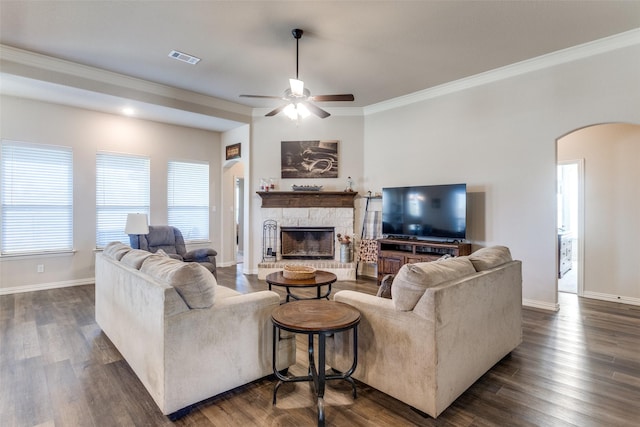 living room featuring ornamental molding, a stone fireplace, ceiling fan, and dark hardwood / wood-style flooring