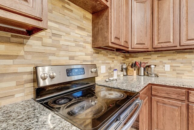 kitchen with light stone counters, range with electric cooktop, and tasteful backsplash