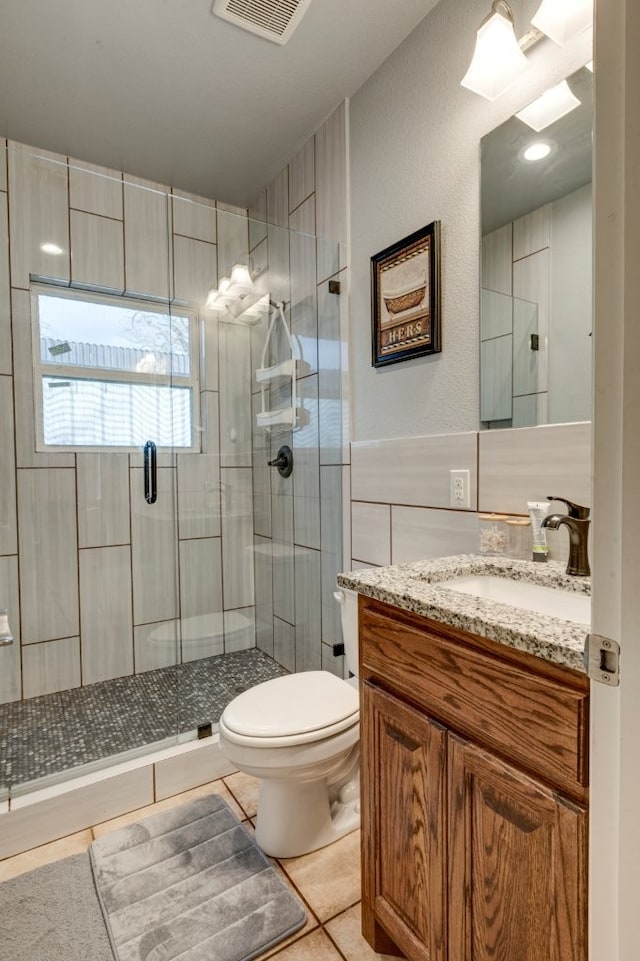 bathroom featuring vanity, tile patterned flooring, toilet, walk in shower, and tile walls