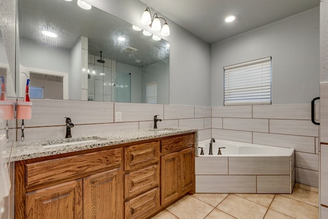 bathroom with shower with separate bathtub, vanity, tile patterned floors, and tile walls