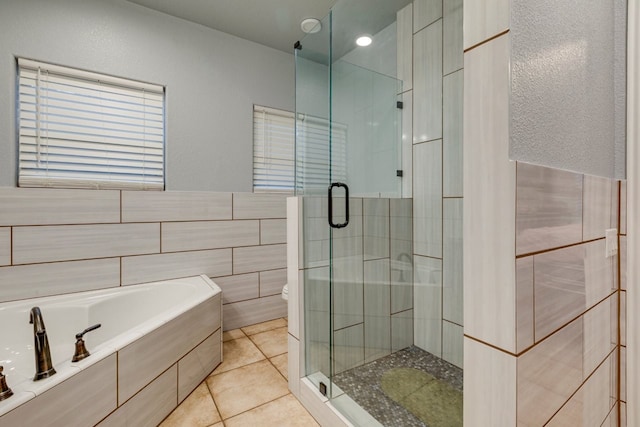 bathroom with tile patterned flooring, separate shower and tub, tile walls, and toilet