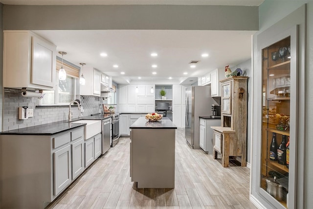 kitchen featuring appliances with stainless steel finishes, sink, pendant lighting, light hardwood / wood-style floors, and a kitchen island