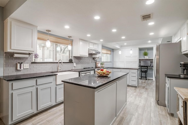 kitchen featuring decorative light fixtures, a center island, white cabinetry, and sink