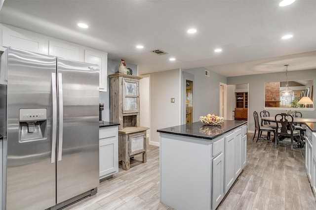 kitchen with a center island, stainless steel refrigerator with ice dispenser, light wood-type flooring, decorative light fixtures, and white cabinetry