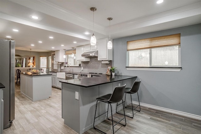 kitchen with a breakfast bar area, kitchen peninsula, white cabinets, and hanging light fixtures