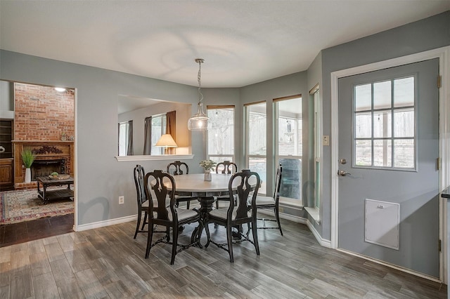 dining area with wood-type flooring and a brick fireplace