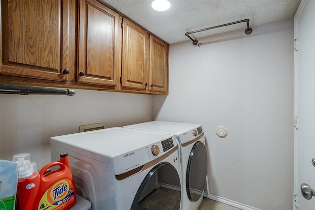 laundry area featuring cabinets, a textured ceiling, and washing machine and dryer