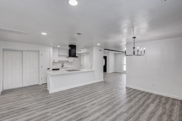 kitchen featuring sink, white cabinetry, hanging light fixtures, ventilation hood, and light wood-type flooring