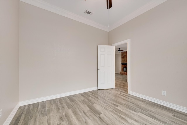 empty room with crown molding, ceiling fan, a fireplace, and light hardwood / wood-style flooring