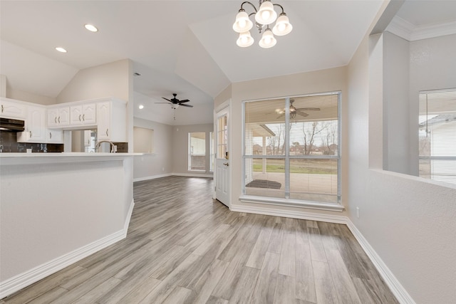 interior space with an inviting chandelier, tasteful backsplash, kitchen peninsula, white cabinets, and light wood-type flooring