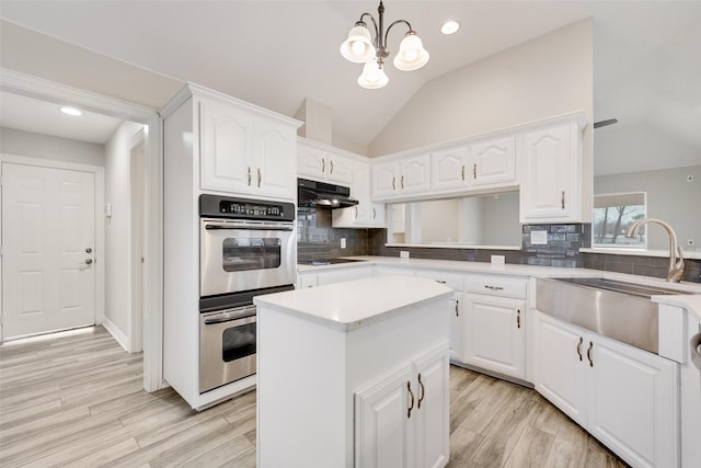 kitchen featuring white cabinets, decorative light fixtures, and lofted ceiling