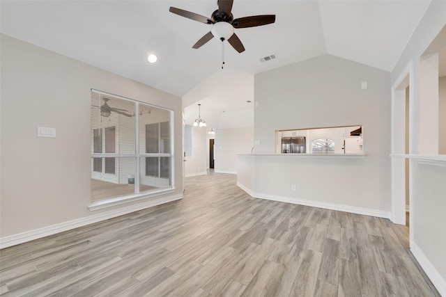 unfurnished living room featuring ceiling fan with notable chandelier, light hardwood / wood-style floors, and lofted ceiling