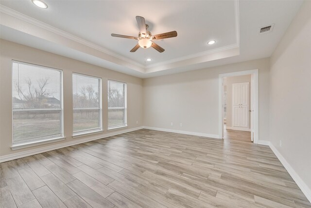 unfurnished room featuring light wood-type flooring, a tray ceiling, and ceiling fan