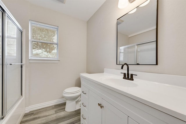 full bathroom featuring hardwood / wood-style flooring, bath / shower combo with glass door, vanity, and toilet