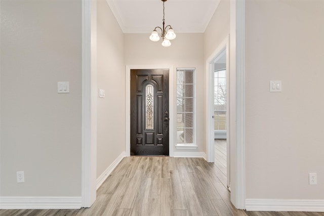 foyer with ornamental molding, a chandelier, and light wood-type flooring