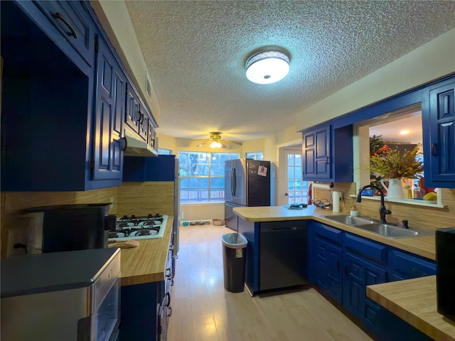 kitchen with tasteful backsplash, freestanding refrigerator, blue cabinetry, gas stovetop, and a sink