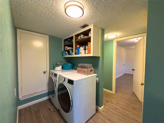 laundry room with a textured ceiling, light wood-style flooring, laundry area, baseboards, and independent washer and dryer