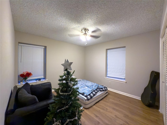 bedroom with ceiling fan, wood-type flooring, and a textured ceiling