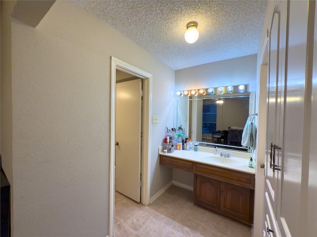 bathroom featuring baseboards, a textured wall, tile patterned floors, a textured ceiling, and vanity