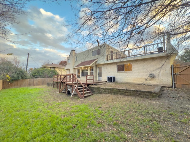 rear view of property featuring a deck, a fenced backyard, central AC, brick siding, and a yard