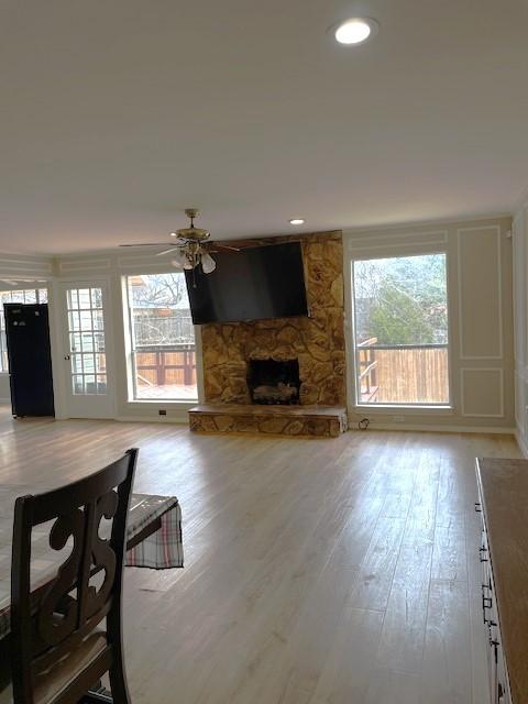 living area with a healthy amount of sunlight, light wood-style flooring, a fireplace, and ceiling fan