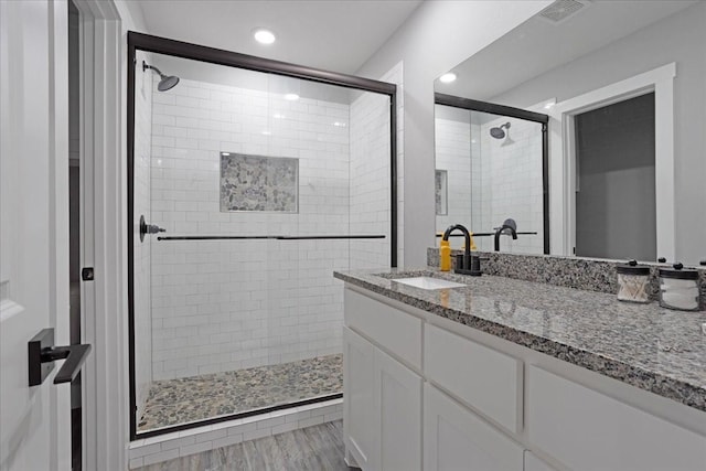 bathroom with vanity, wood-type flooring, and a shower with door