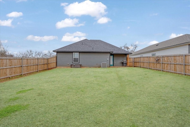 rear view of house with central AC unit and a lawn