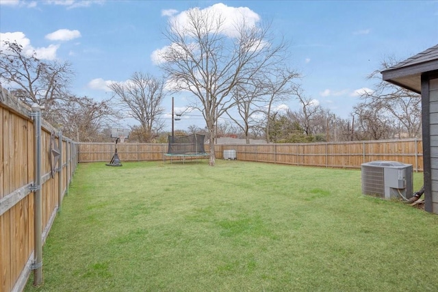 view of yard featuring a trampoline and central AC