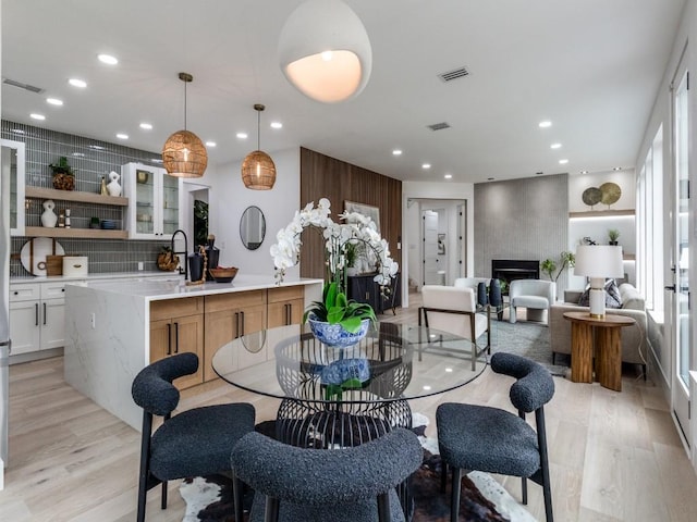 dining space with a large fireplace, sink, and light hardwood / wood-style floors