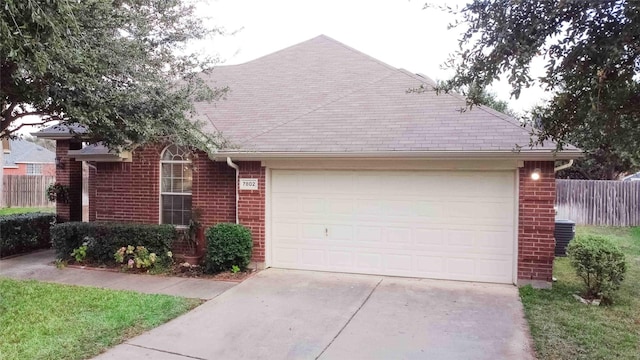 view of front of property featuring a garage, fence, brick siding, and driveway