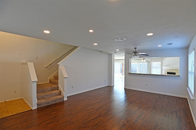 unfurnished living room featuring dark hardwood / wood-style flooring, a tile fireplace, and ceiling fan