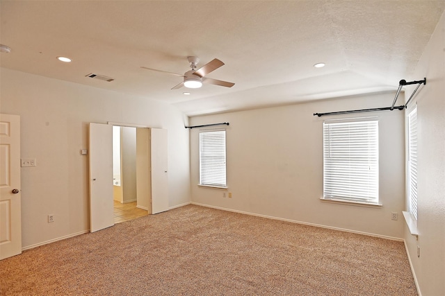 empty room featuring ceiling fan, vaulted ceiling, and light carpet