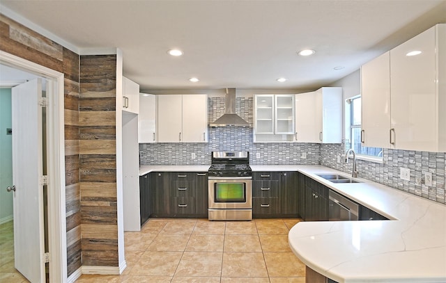 kitchen with a sink, stainless steel appliances, wall chimney exhaust hood, and white cabinets