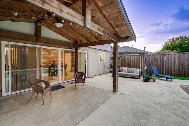 patio terrace at dusk featuring an outdoor living space, ceiling fan, and fence