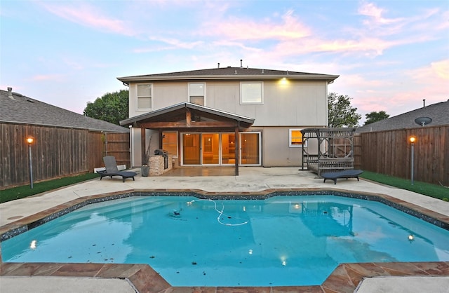 pool at dusk featuring a pergola and a patio