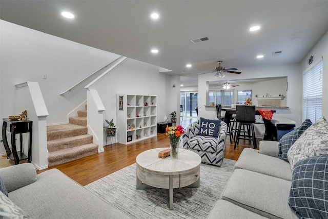 living area with stairs, wood finished floors, visible vents, and ceiling fan