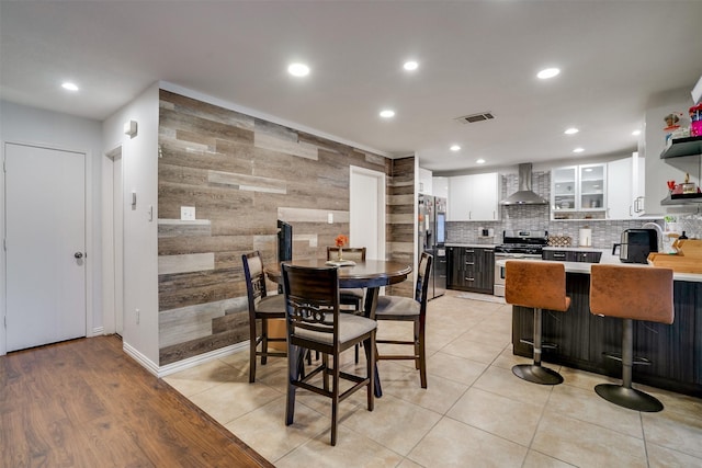 dining area featuring sink, light tile patterned floors, and wooden walls