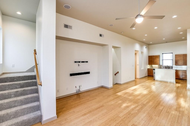 unfurnished living room featuring ceiling fan, sink, and light wood-type flooring