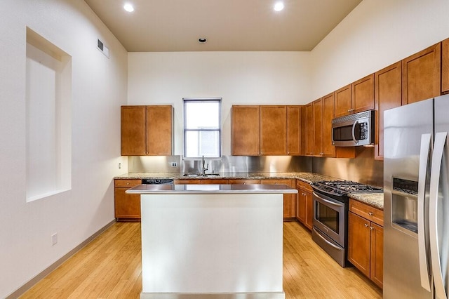 kitchen with a kitchen island, appliances with stainless steel finishes, sink, and light hardwood / wood-style floors