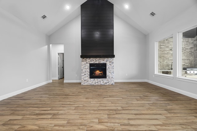 unfurnished living room with a fireplace, light hardwood / wood-style floors, and high vaulted ceiling