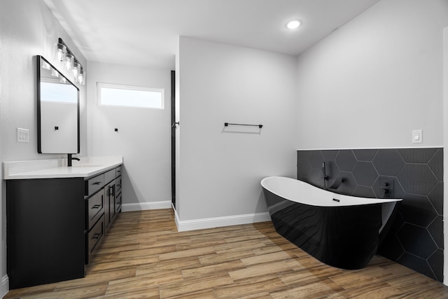 bathroom with vanity, wood-type flooring, and a bath