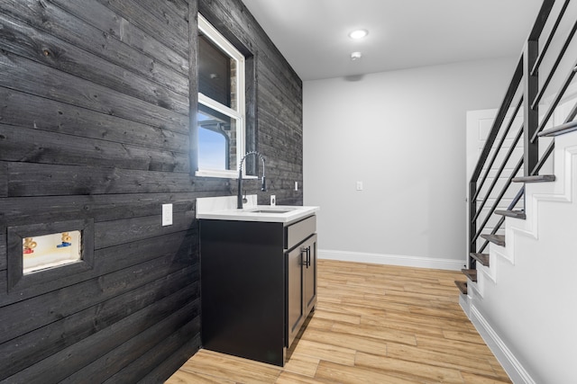 kitchen featuring light wood-type flooring, wooden walls, and sink