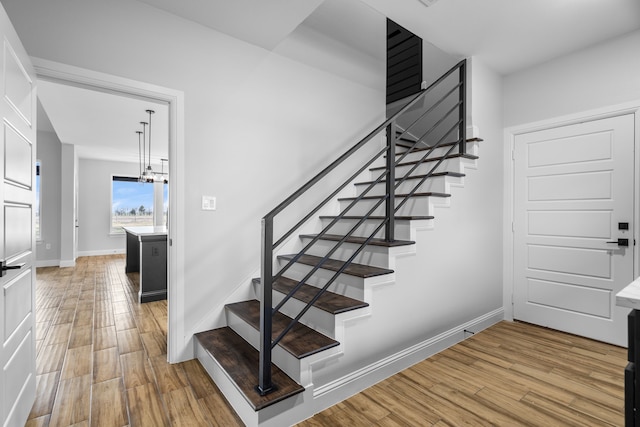 stairway featuring hardwood / wood-style flooring and an inviting chandelier