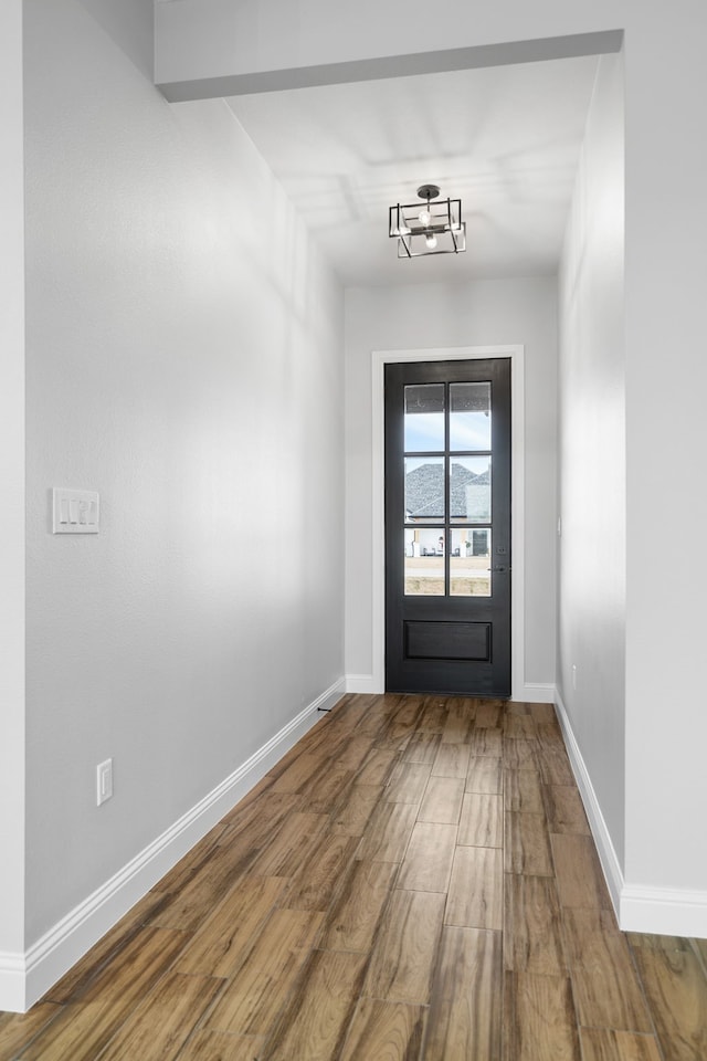 doorway to outside featuring wood-type flooring and a notable chandelier