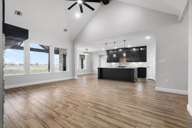 unfurnished living room with hardwood / wood-style floors, ceiling fan with notable chandelier, beamed ceiling, and high vaulted ceiling