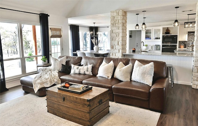 living room featuring sink, light hardwood / wood-style floors, vaulted ceiling, and a notable chandelier